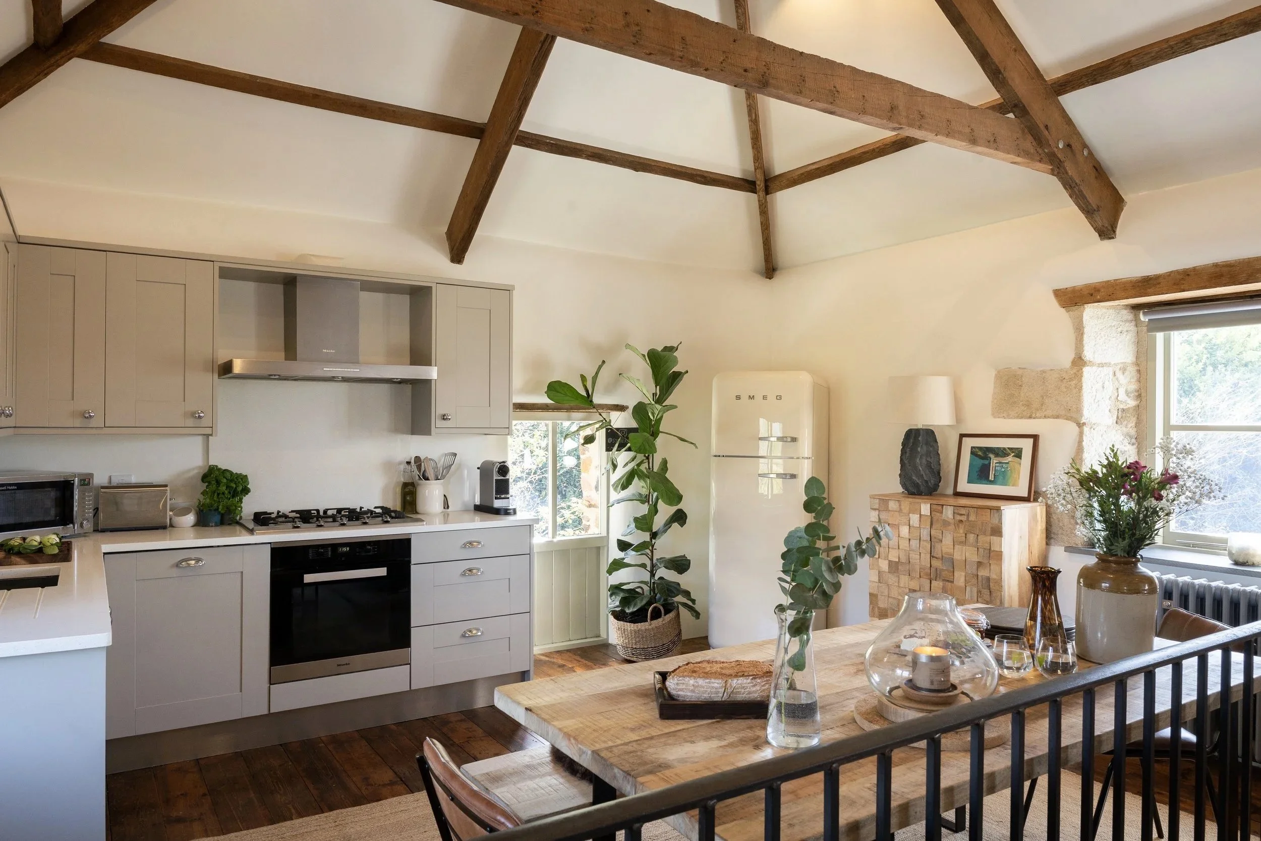 Open-plan kitchen and dining area with beams and soft light at Stargazey.