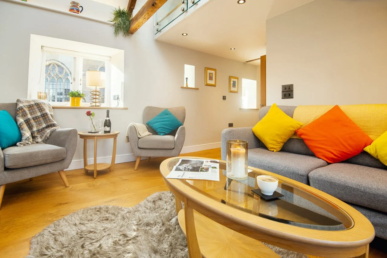 Living room with gray sofas, colorful cushions, wooden coffee table, and a shaggy rug.