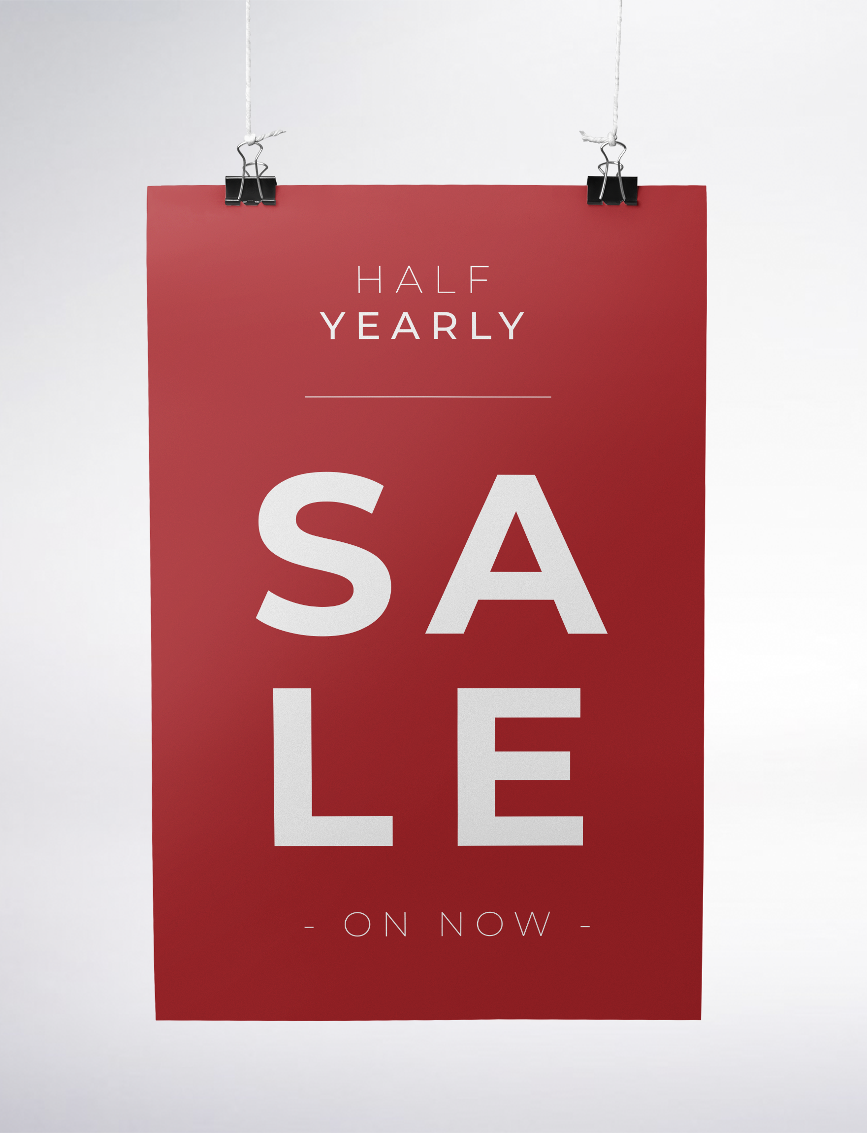 Red sale sign hanging with black clips that reads 'Half Yearly Sale On Now' in white text.