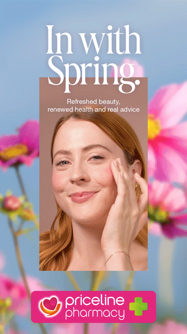A woman with red hair touching her face, standing in front of pink flowers with a light blue background, promoting spring skincare and health advice from Priceline Pharmacy.