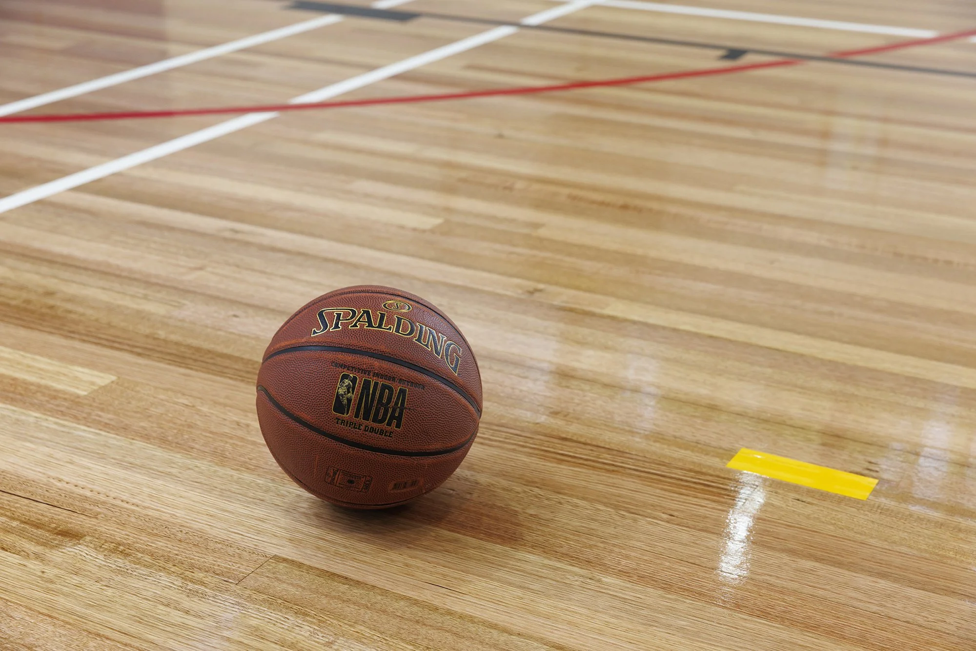 A basketball resting on a polished wooden court with painted lines.