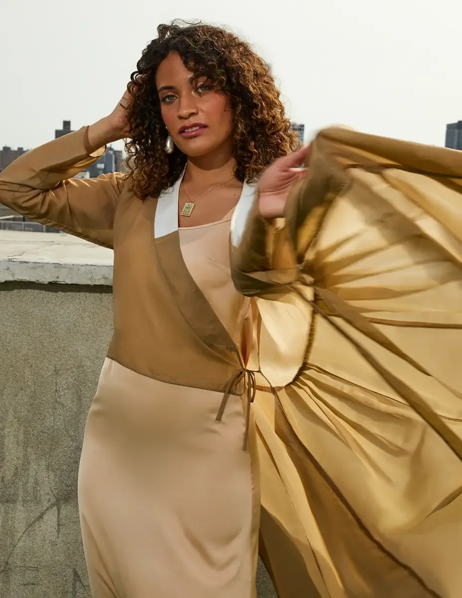 Fashion test shoot, model Ireland T in a gold satin wrap dress with white collar and tie belt, skirt in motion, Taro Collection earrings, East Village rooftop, New York City, styling by Matsine Stinson, makeup by Stefani Paige Vivian, photographed by