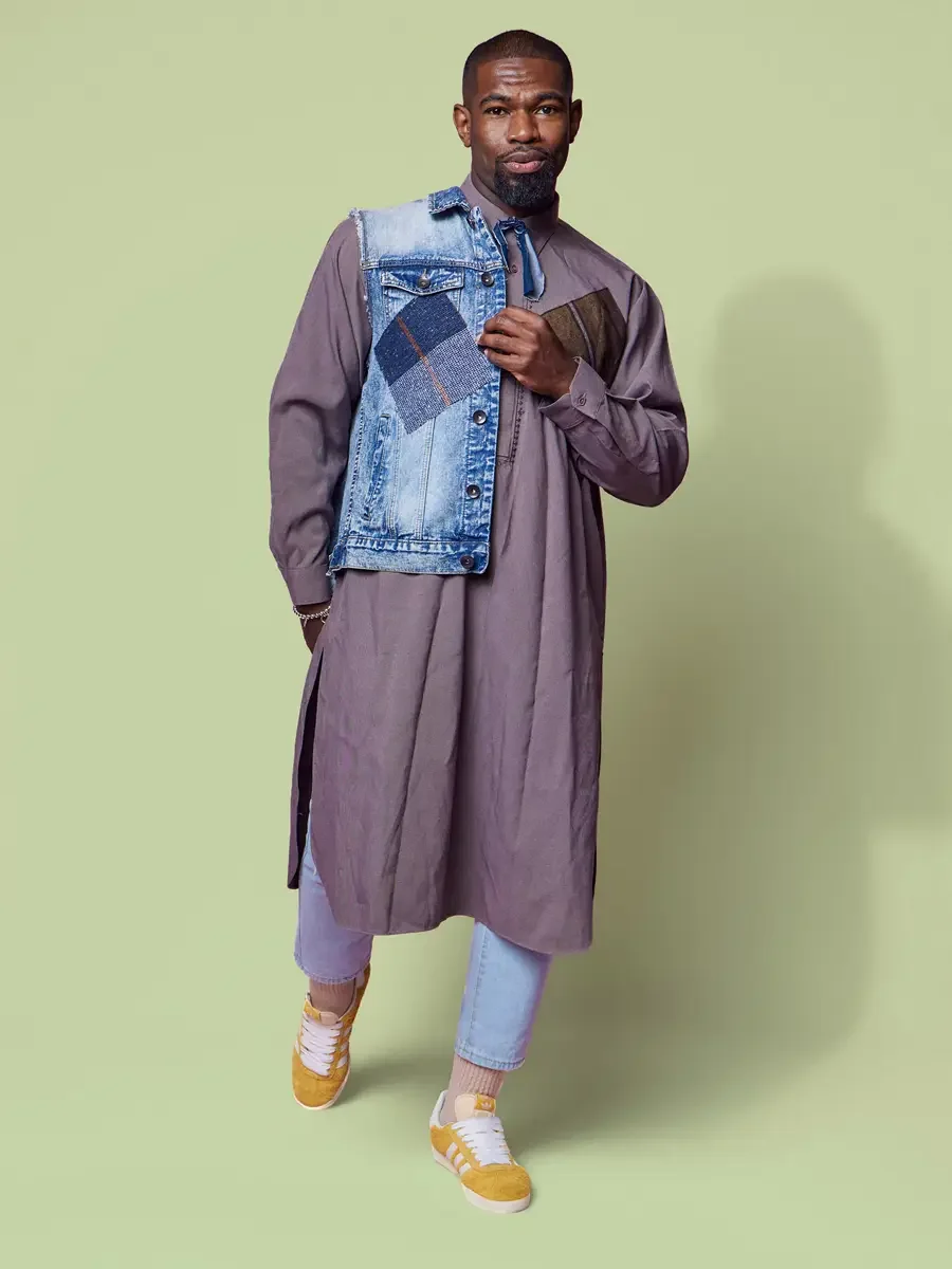 JUS10H 2025 content library, model in mauve longline shirt-dress with patchwork denim vest carried against chest, light blue trousers and yellow sneakers, sage green background, photographed by Scott Parker Photo
