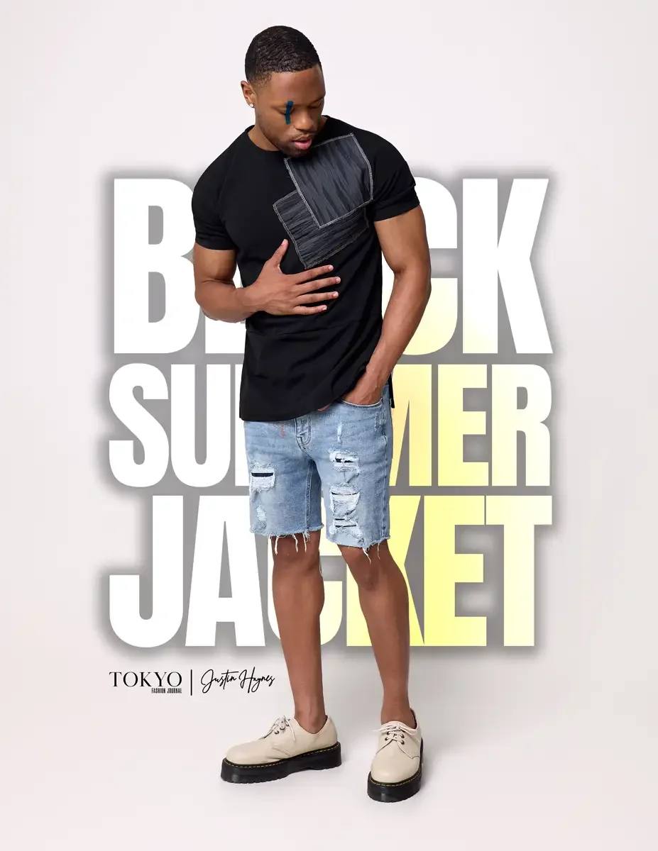 JUS10H Black Summer Jacket lookbook, male model in black fitted tee with gray patchwork chest detail, distressed denim shorts, tan lace-up shoes, white background, photographed by Scott Parker Photo