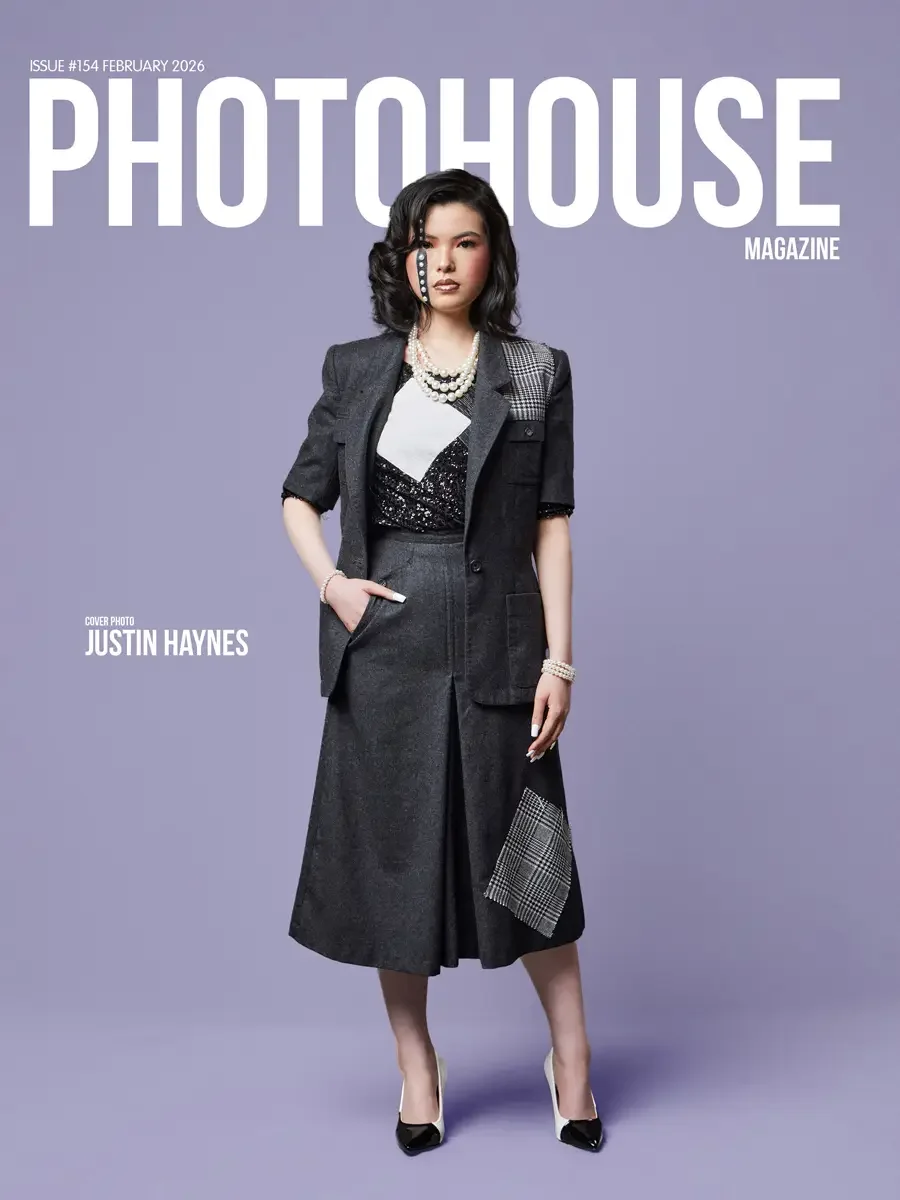 JUS10H 2025 Photohouse Magazine feature, cover image, model in charcoal short-sleeve blazer and glen plaid patchwork panel over black sequin top and pleated midi skirt with matching glen plaid hem patch, layered pearl necklace, lavender background, p
