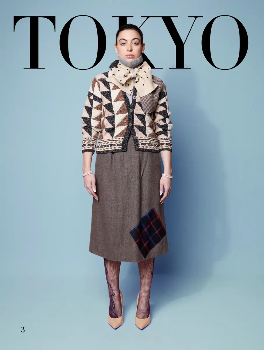 JUS10H 2025 Tokyo lookbook, geometric knit cardigan over brown midi skirt with tartan patch and polka dot neck scarf, light blue background, photographed by Scott Parker Photo for the Tokyo Fashion Council