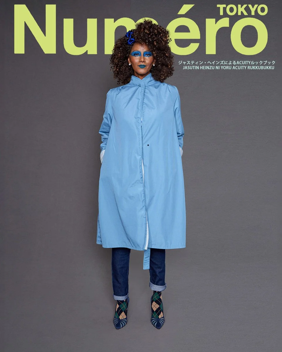 JUS10H by Justin Haynes ACUITY Collection lookbook for Numéro Tokyo by Scott Parker — model in light blue cotton funnel-neck duster coat with belt detail, layered over dark wash cuffed jeans and finished with green argyle-print pointed-toe pumps.