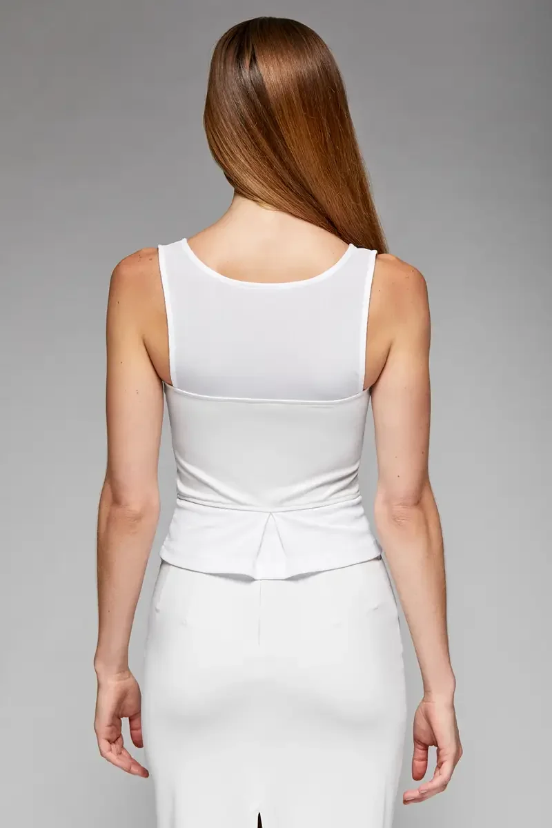Minika Ko lookbook, white peplum corset top, back view, scoop back neckline, peplum pleat detail at center back, smooth matte-finish semi-water-repellent synthetic, gray background, photographed by Scott Parker Photo