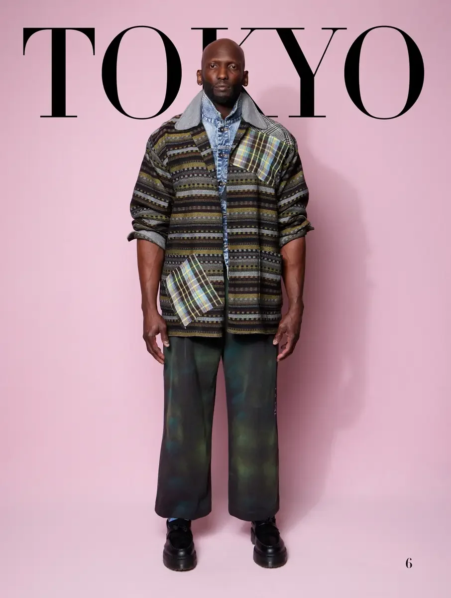 JUS10H 2025 Tokyo lookbook, multi-stripe textured jacket with tartan patch over denim shirt and dark tie-dye wide leg trousers, pink background, photographed by Scott Parker Photo for the Tokyo Fashion Council