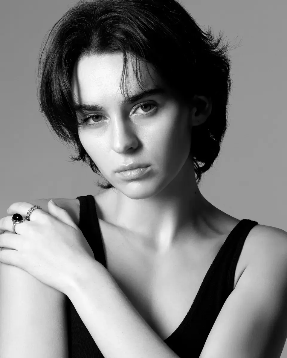 Tess, three-quarter crop, arms crossed at chest, dark oval stone ring and silver band ring, black tank top, gray background, black and white, New York studio test shoot, makeup by Schanica, photographed by Scott Parker Photo