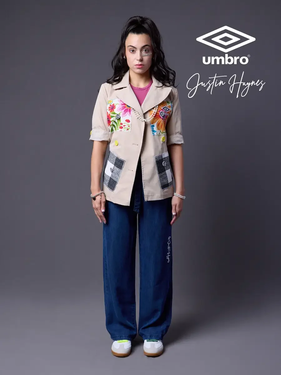 Refined football style for the Umbro France collection. Vanessa standing front-facing in a sand utility jacket with floral patchwork panels over a fuchsia t-shirt and wide-leg dark indigo jeans, styled by Justin Haynes, photographed in Springfield, M