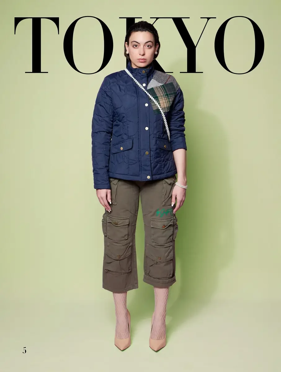 JUS10H 2025 Tokyo lookbook, navy quilted jacket with tartan patch over olive cargo capri pants and fishnet tights, sage green background, photographed by Scott Parker Photo for the Tokyo Fashion Council