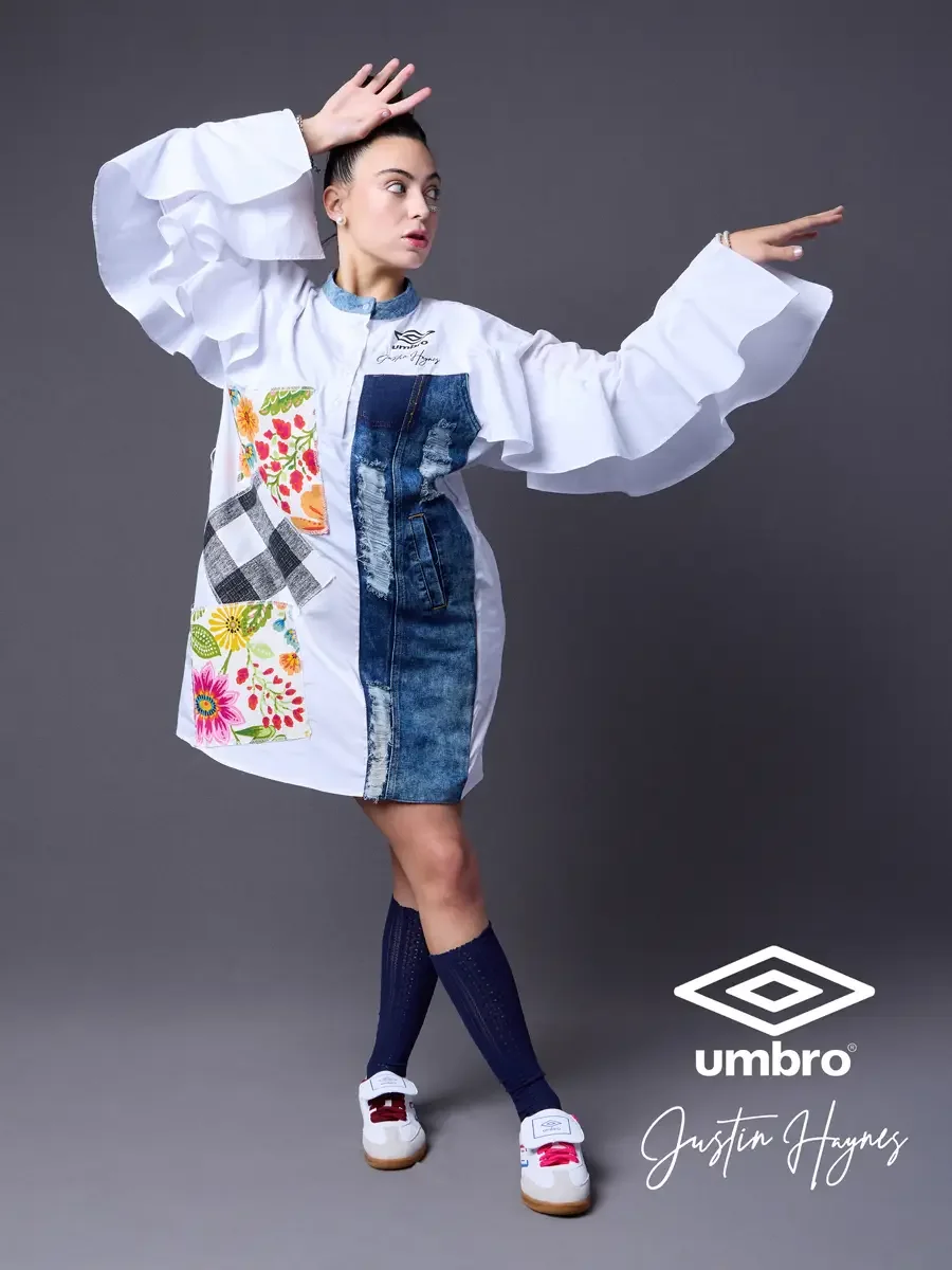 Fashion lifestyle photography for the Umbro France collection. Vanessa in motion with arms extended wide displaying the ruffled sleeves of an oversized white shirt dress with a distressed denim center panel and floral patchwork, styled by Justin Hayn