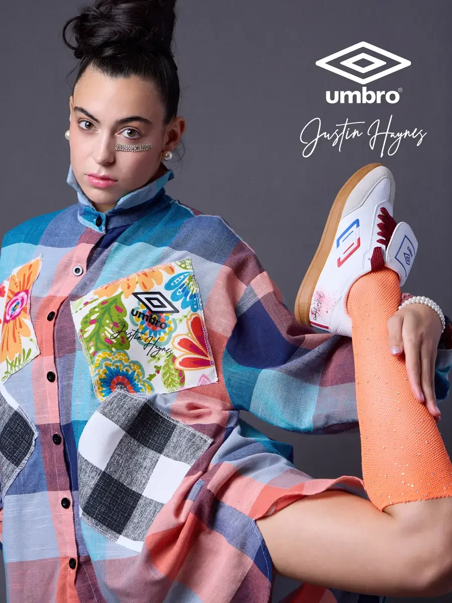 Fashion brand photography for the Umbro France collection. Vanessa in a close detail shot with one leg raised showing the floral patchwork panels and Umbro France sneaker of an oversized multicolor plaid shirt dress, styled by Justin Haynes, photogra