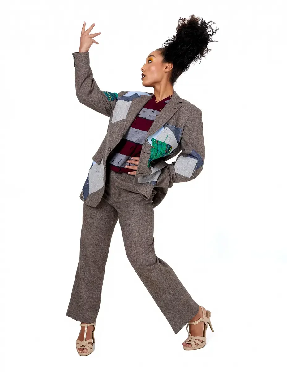 Model portfolio development session, high fashion editorial look, oversized heathered blazer with mixed fabric appliqué panels over burgundy and heather grey destroyed-knit stripe sweater with raw-edge sleeves, straight-leg heathered trousers, nude t