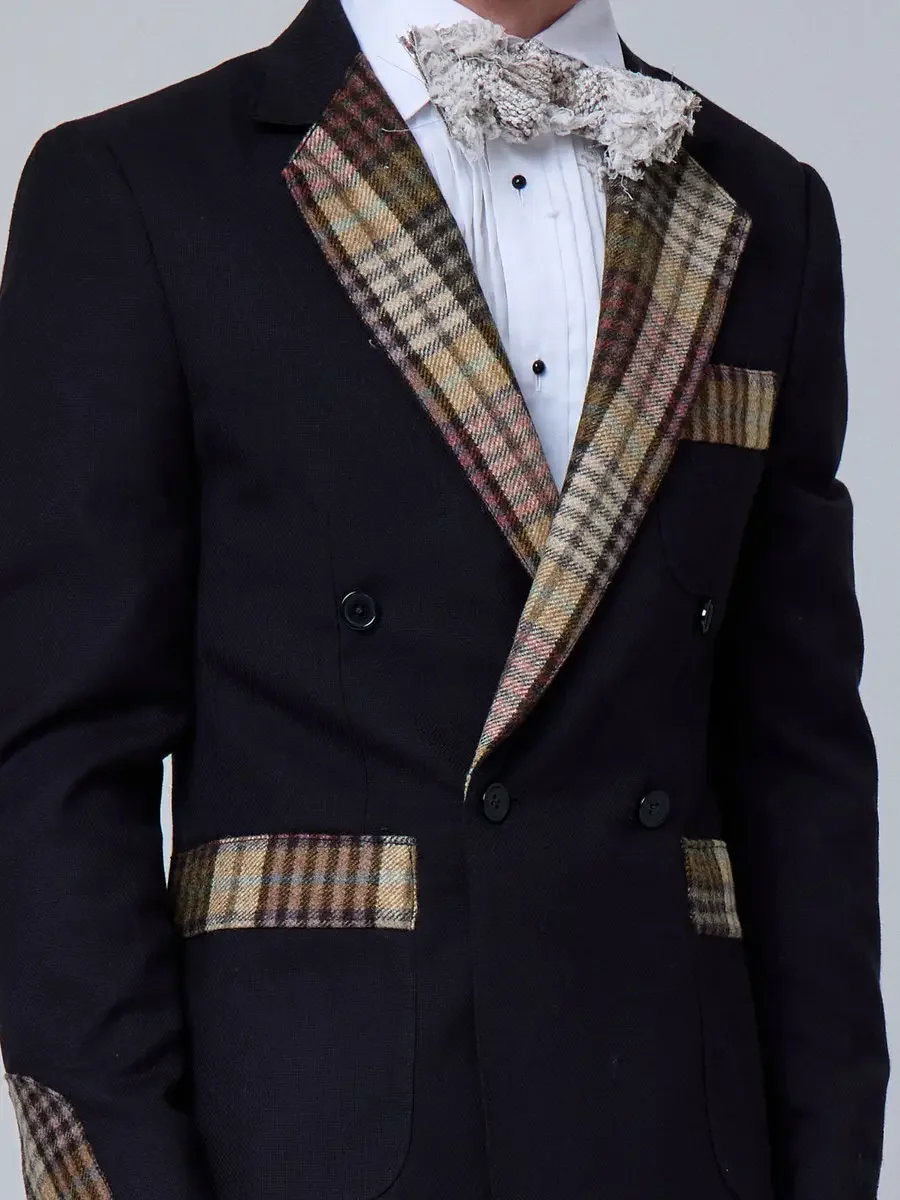 JUS10H 2025 New York Bridal Fashion Week, close detail of black double-breasted suit jacket with multi-tone plaid lapels, matching plaid pocket trim, and dimensional lace bow tie with pleated white dress shirt, photographed by Scott Parker Photo