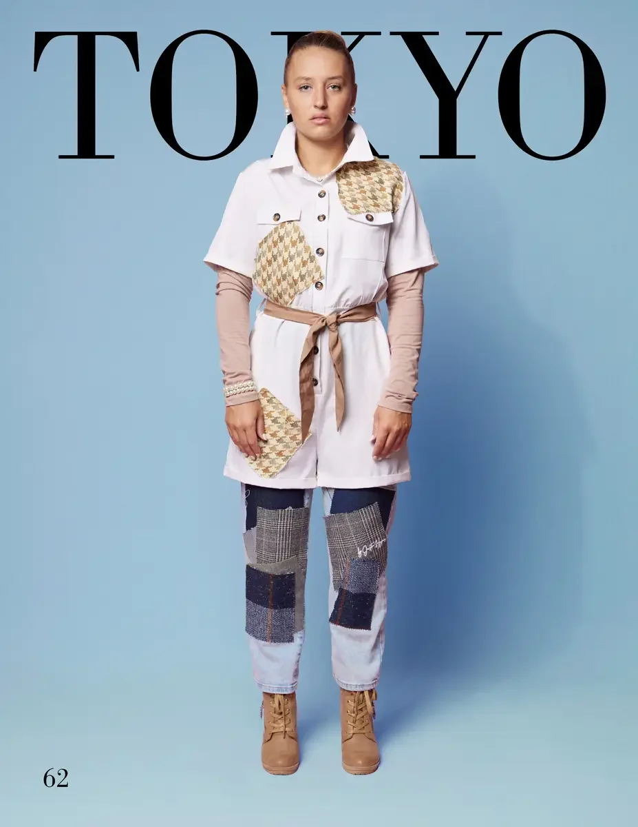 JUS10H 2025 Tokyo lookbook, a female model wearing a white short-sleeve button-front shacket with tan and cream houndstooth patchwork appliqués on the chest and lower front, belted with a tan fabric tie, layered over a blush pink long-sleeve top, pai