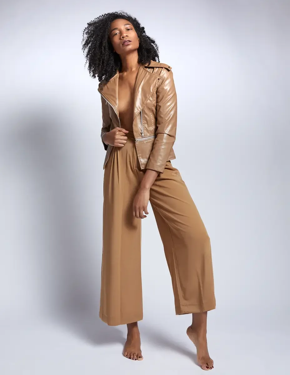 Arielle Chambers, jump shot, camel patent leather moto jacket and wide-leg trousers, East Williamsburg studio test shoot, makeup by Schanica Pickens, photographed by Scott Parker Photo