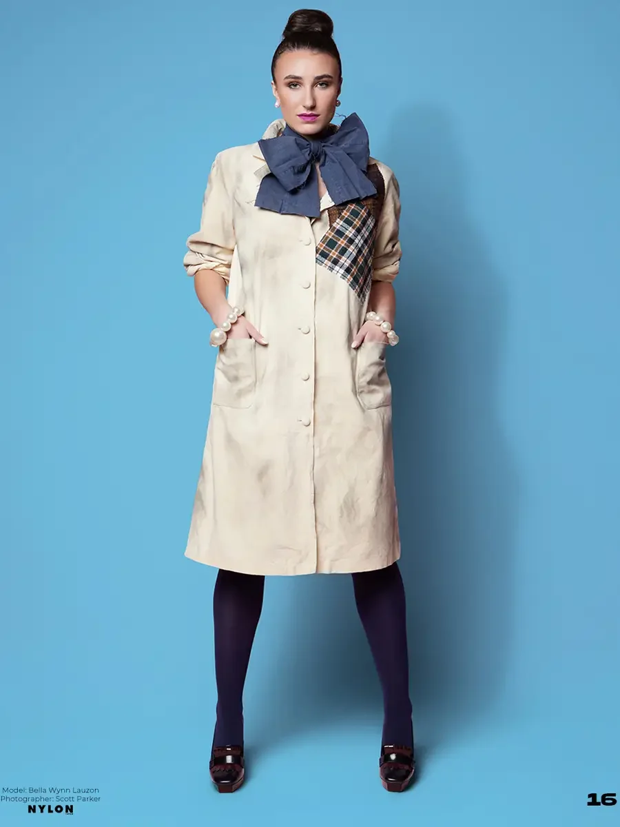 JUS10H 2025 Nylon Japan feature, model in cream button-front midi coat dress with multicolor tartan patchwork panel and oversized denim bow, pearl bracelets, navy tights and burgundy platform loafers, light blue background, photographed by Scott Park