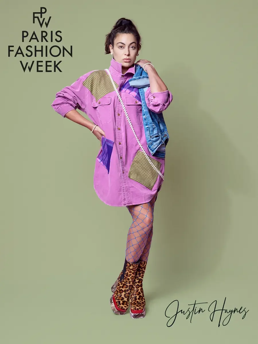 JUS10H 2025 promotional image, model in fuchsia oversized patchwork denim shirtdress with olive houndstooth and purple tartan panels, pearl rope necklace, blue rhinestone fishnet tights and leopard print platform boots, light blue denim jacket draped