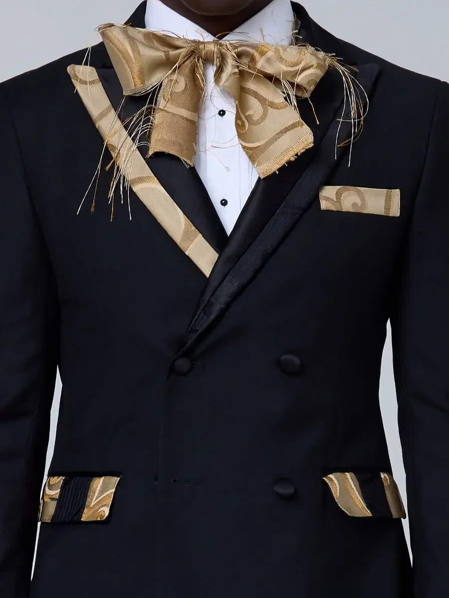 JUS10H 2025 New York Bridal Fashion Week, close detail of black double-breasted tuxedo with gold jacquard lapels, pocket trim, and oversized gold jacquard bow tie with raw-edge fringe detail and matching pocket square, photographed by Scott Parker Ph