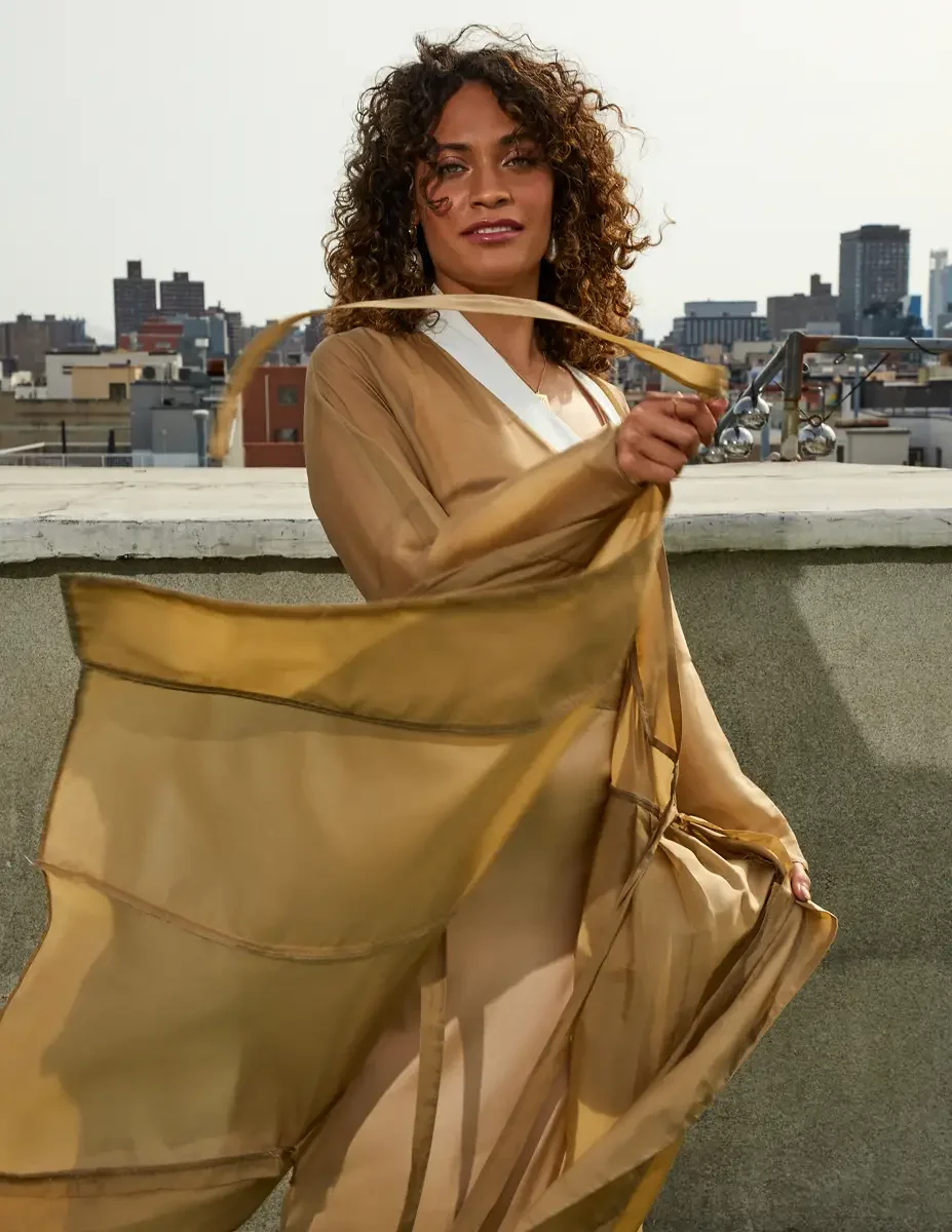 Fashion test shoot, model Ireland T in a gold satin wrap dress, skirt caught in the wind, Manhattan skyline, East Village rooftop, New York City, styling by Matsine Stinson, makeup by Stefani Paige Vivian, photographed by Scott Parker Photo