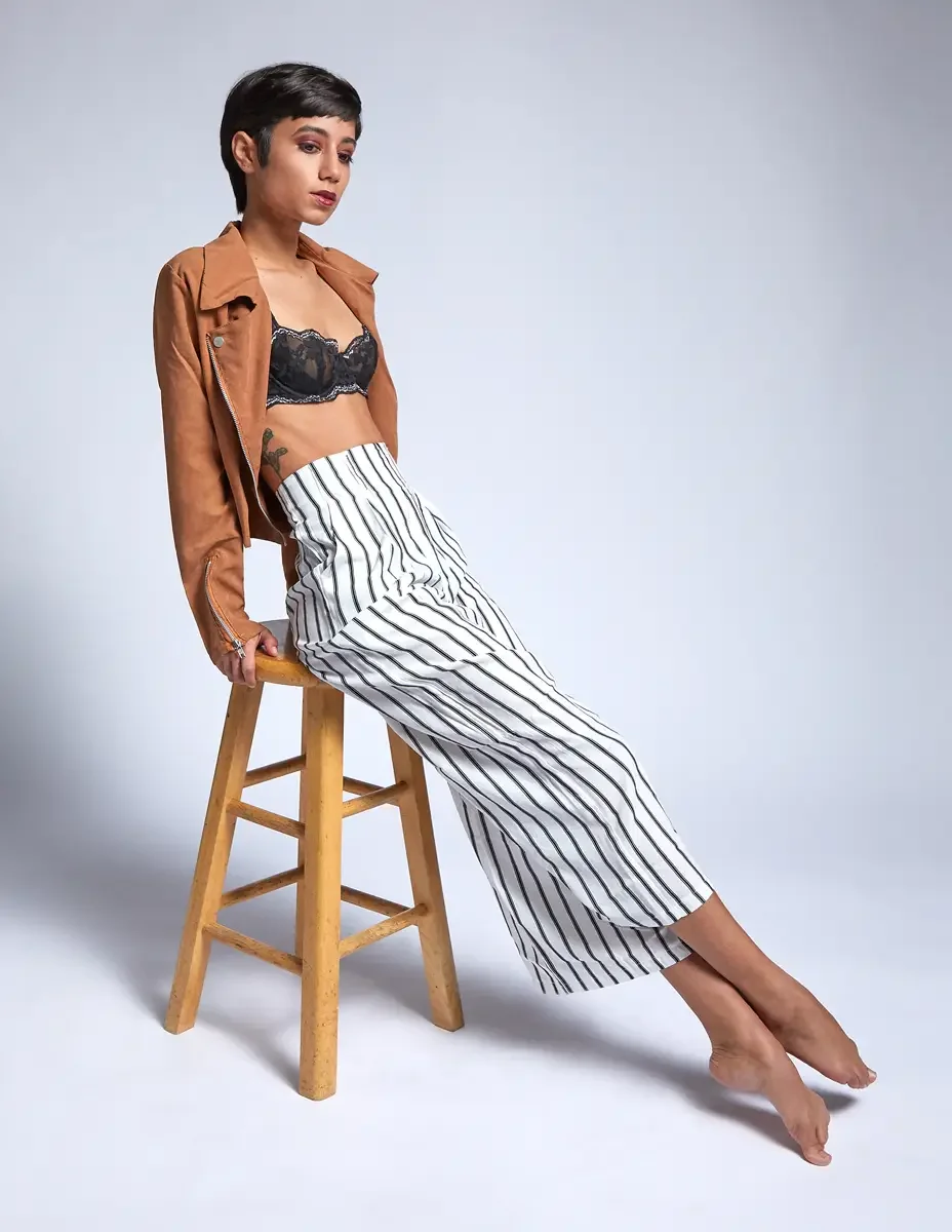 Eloissa, seated lean, striped high-waisted wide-leg trousers and tan suede jacket, black lace bralette, studio stool, East Williamsburg studio test shoot, makeup by Schanica Pickens, photographed by Scott Parker Photo