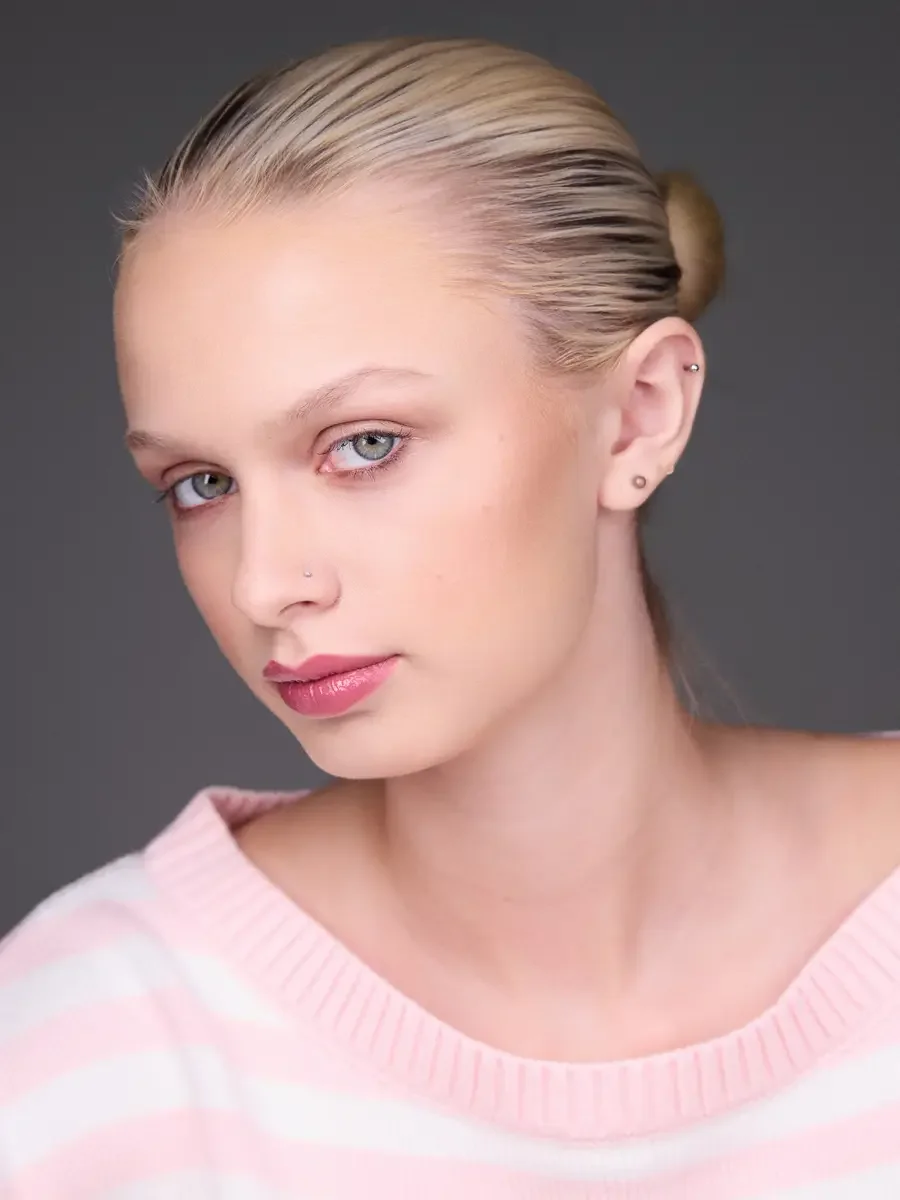 Model portfolio development session, beauty, close-crop, hair in low bun, three-quarter turn, direct gaze, rose lip, soft eye, pink striped sweater, gray background, photographed by Scott Parker Photo, New York