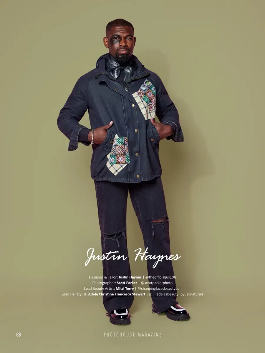JUS10H 2025 Photohouse Magazine feature, model in dark navy denim field jacket with multicolor embroidered and tartan patchwork panels over black wide-leg distressed jeans and leather neck scarf, sage green background, photographed by Scott Parker Ph
