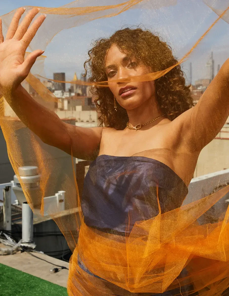 Fashion test shoot, model Ireland T in Amy Page DeBlasio navy strapless top and textured blue wide-leg pants, orange tulle in motion, East Village rooftop, New York City, styling by Matsine Stinson, makeup by Stefani Paige Vivian, photographed by Sco