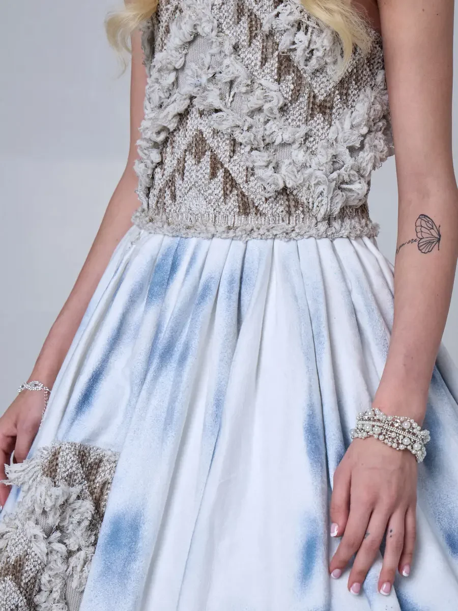 JUS10H 2025 New York Bridal Fashion Week, close detail of dimensional lace strapless bodice transitioning into an ice-blue tie-dye ball gown skirt with lace patch appliqué, styled with stacked pearl and crystal bracelets, photographed by Scott Parker