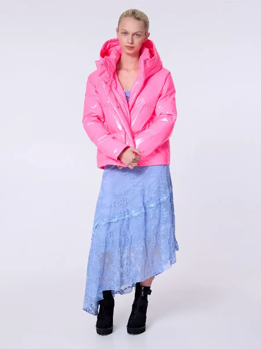 Model portfolio development session, commercial look, hot pink vinyl puffer jacket with hood over periwinkle blue lace asymmetrical midi dress, full-length, facing camera, hands clasped at front of jacket hem, composed expression, asymmetrical lace h