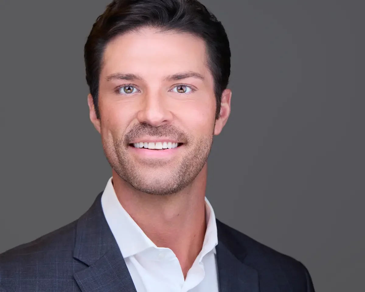 Nonprofit executive director headshot, charcoal blazer and white shirt, warm confident expression, gray background, Litchfield County Connecticut, photographed by Scott Parker Photo