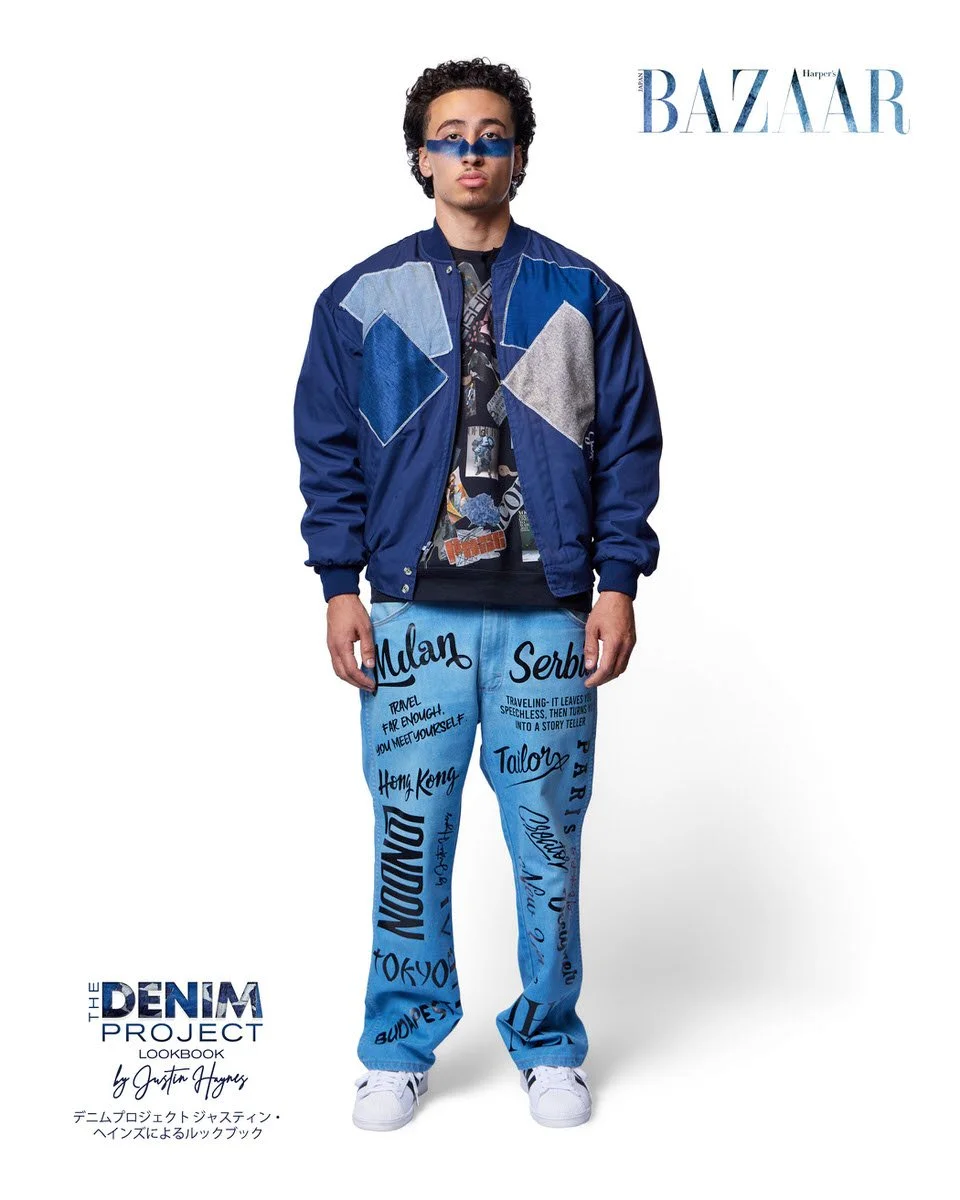 JUS10H Denim Project 2025 Harper's Bazaar Japan lookbook — male model in navy denim-patchwork bomber jacket over hand-lettered city-name light-wash jeans printed with travel quotes and global destinations including Milan, London, Tokyo, Paris, fashio