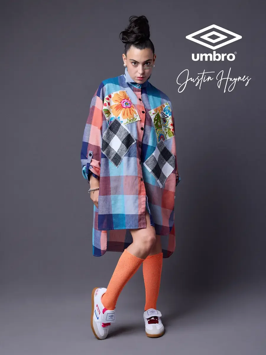 Fashion photographer in Massachusetts for the Umbro France collection. Vanessa in a three-quarter stance with one leg crossed in an oversized multicolor plaid shirt dress with floral patchwork panels and orange football knee socks, styled by Justin H