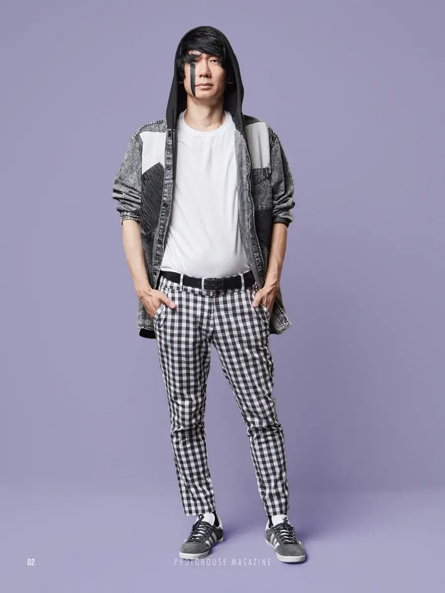 JUS10H 2025 Photohouse Magazine feature, model in acid-wash denim hooded jacket with geometric patchwork panels over white tee and black and white gingham trousers, lavender background, photographed by Scott Parker Photo
