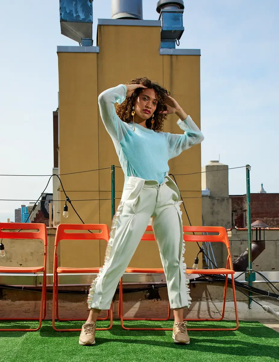 Fashion test shoot, full-length, model Ireland T in Amy Page DeBlasio white ruffle-trim pants and aqua sheer knit top, East Village rooftop, New York City, styling by Matsine Stinson, makeup by Stefani Paige Vivian, photographed by Scott Parker Photo