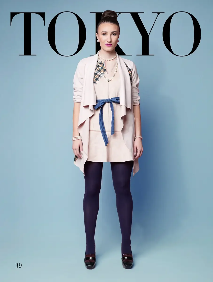 JUS10H 2025 Tokyo lookbook, a model wearing a blush pink waterfall-lapel cardigan coat with plaid panel details at the sides over a blush pink mini dress, cinched with a denim bow belt, styled with layered pearl necklaces, pearl bracelets, navy tight