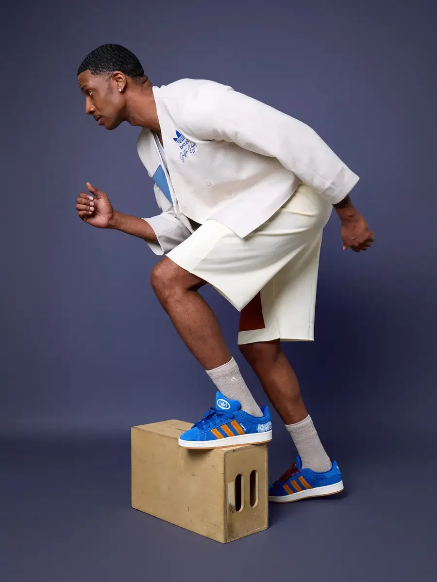 JUS10H x Adidas Brasil campaign, model stepping up onto wood block in profile, white patchwork open robe jacket with blue and terracotta suede panels over cream patchwork shorts, Adidas Campus 00s in royal blue suede with orange stripes, periwinkle b