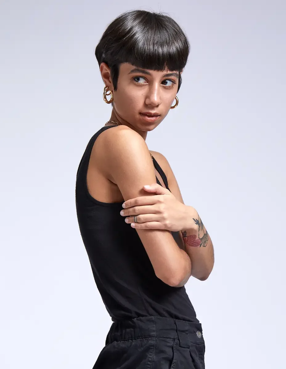 Eloissa, over-shoulder portrait, black tank, gold hoop earrings, floral forearm tattoo, East Williamsburg studio test shoot, makeup by Schanica Pickens, photographed by Scott Parker Photo
