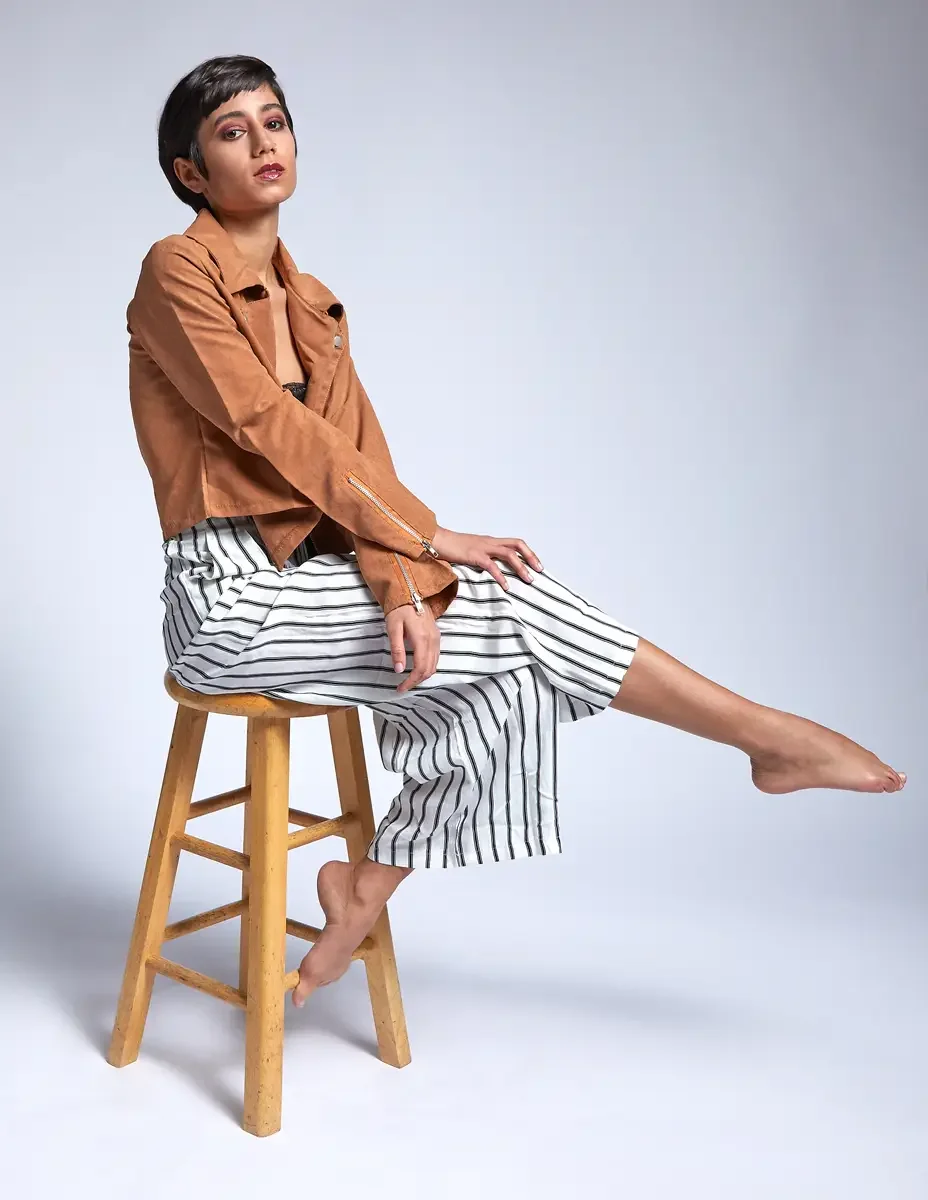 Eloissa, seated, leg extended, tan suede cropped jacket and striped wide-leg trousers, studio stool, East Williamsburg studio test shoot, makeup by Schanica Pickens, photographed by Scott Parker Photo