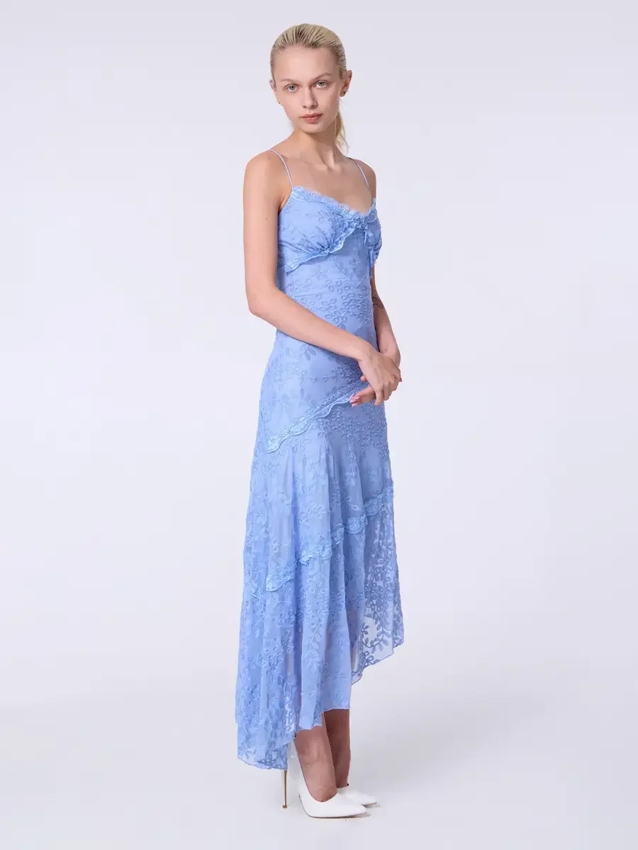 Model portfolio development session, commercial look, periwinkle blue lace asymmetrical midi dress with ruffle bodice detail and spaghetti straps, full-length, three-quarter turn, direct gaze, hands clasped at waist, bodice ruffle and diagonal tier s