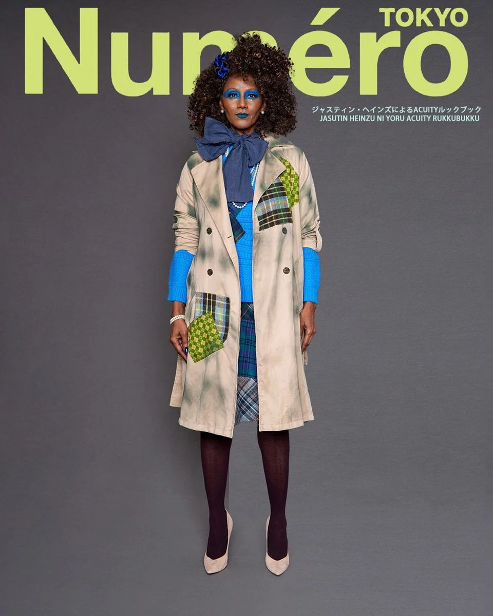 JUS10H by Justin Haynes ACUITY Collection lookbook for Numéro Tokyo by Scott Parker — model in cream and forest green tie-dye double-breasted trench coat with green checkered and tartan patchwork pockets, oversized navy bow at neck, layered over coba