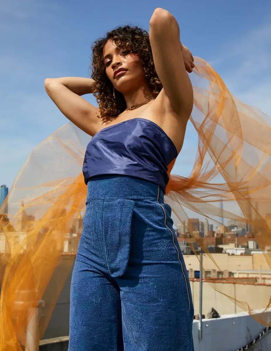 Fashion test shoot, model Ireland T in Amy Page DeBlasio wide-leg textured blue pants with zipper detail and navy strapless top, orange tulle, East Village rooftop, New York City, styling by Matsine Stinson, makeup by Stefani Paige Vivian, photograph