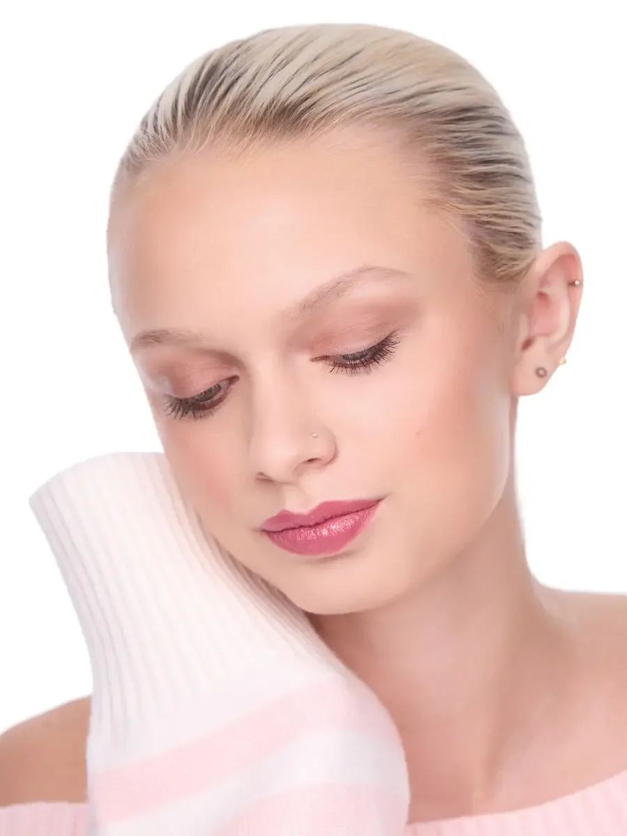 Model portfolio development session, beauty, close-crop, hair slicked back, three-quarter turn, eyes closed, rose lip, soft eye, pink ribbed sweater held against cheek, white background, photographed by Scott Parker Photo, New York