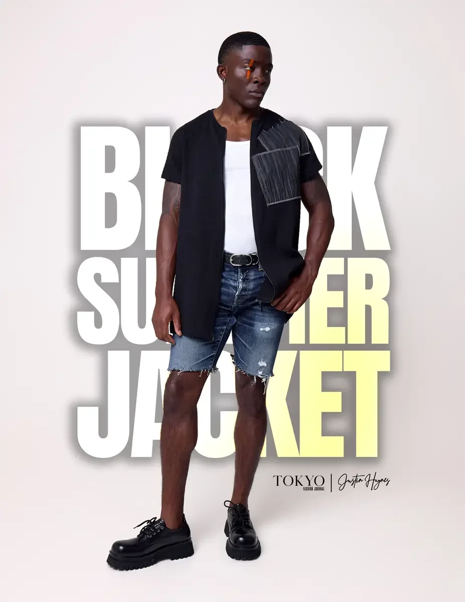 JUS10H Black Summer Jacket lookbook, male model in black collarless short-sleeve jacket with gray patchwork shoulder panel worn open over white tee, distressed denim shorts, black lace-up boots, white background, photographed by Scott Parker Photo