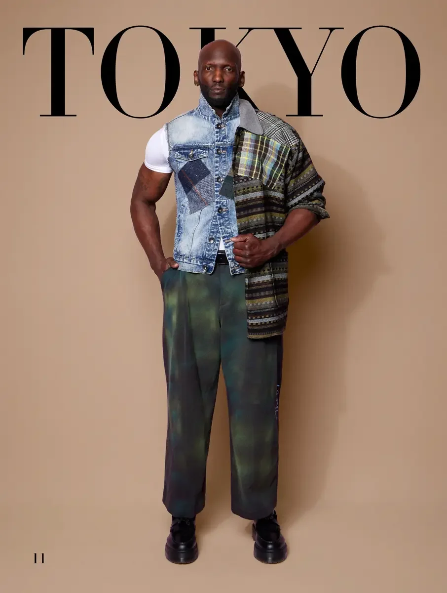 JUS10H 2025 Tokyo lookbook, patchwork denim vest over multi-stripe textured shirt and tie-dye wide leg dark trousers, tan background, photographed by Scott Parker Photo for the Tokyo Fashion Council