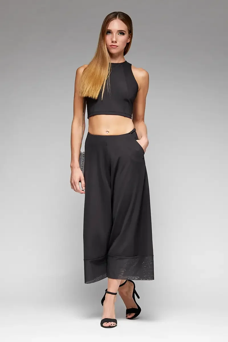 Minika Ko lookbook, black halter crop top and wide-leg culottes set, front view, high waist, side pockets, sheer mesh cuff at hem, smooth synthetic fabric, photographed by Scott Parker Photo