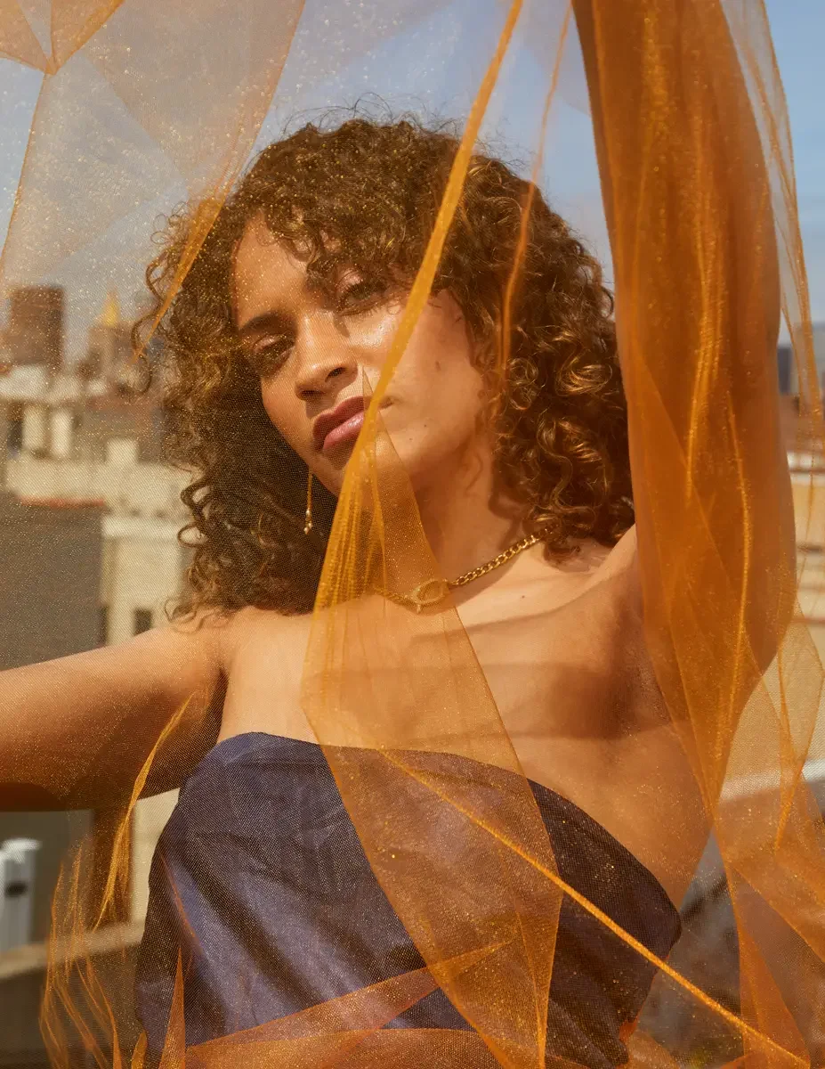 Fashion test shoot, close portrait of model Ireland T in Amy Page DeBlasio navy strapless top, orange tulle layered across frame, East Village rooftop, New York City, styling by Matsine Stinson, makeup by Stefani Paige Vivian, photographed by Scott P