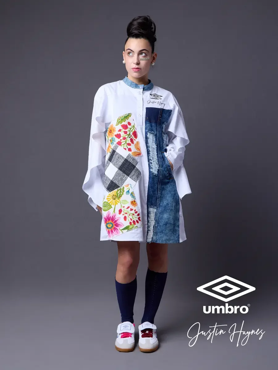 Fashion photographer in Massachusetts for the Umbro France collection. Vanessa in a three-quarter stance glancing sideways in an oversized white shirt dress with dramatic ruffled sleeves, a distressed denim center panel, and floral patchwork, styled 